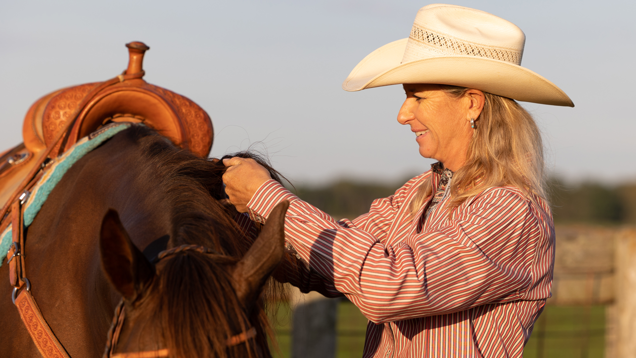 WPRA barrel racer Sherry Cervi adjusting the saddle on her horse.